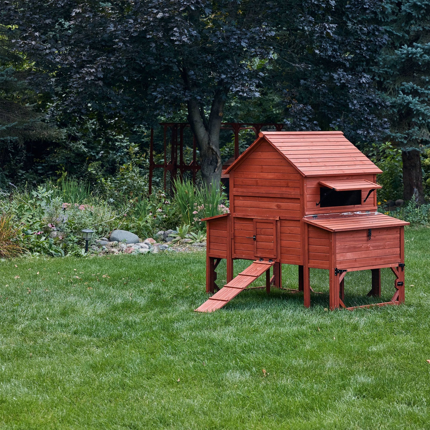 Wooden chicken coop on a grassy area with trees in the background