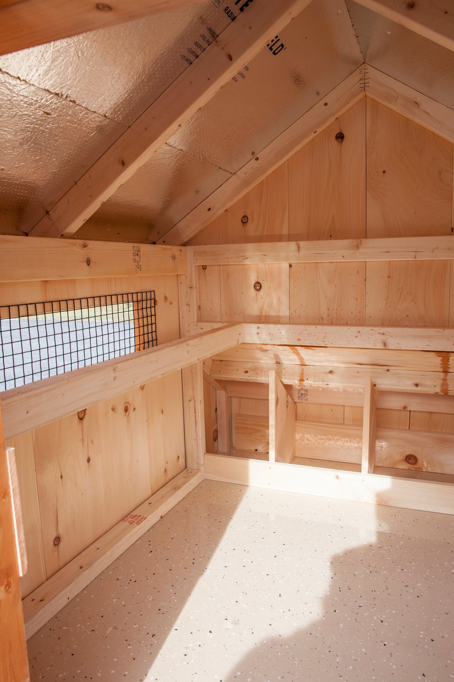 Opposite interior view of Amish-built chicken coop with epoxy floor and screened windows