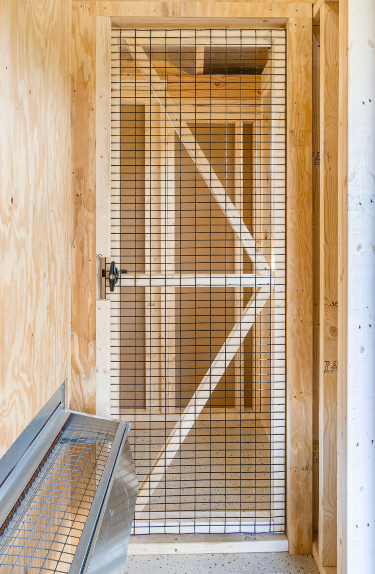 Interior view of A1134RGCD farmhouse chicken coop showing solid wood framing and secure wire access door