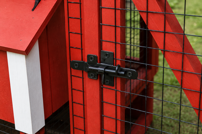 Close-up of the black metal latch and wire mesh door on a red wooden chicken coop run.
