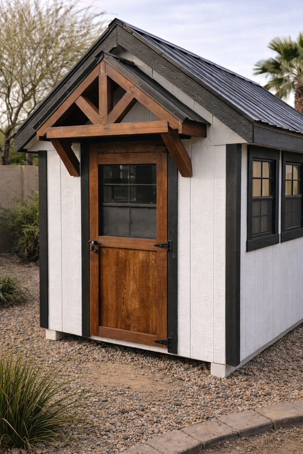 Close-up of modern chicken coop showing white board and batten siding, black trim, metal roof, and solid wood door with hardware