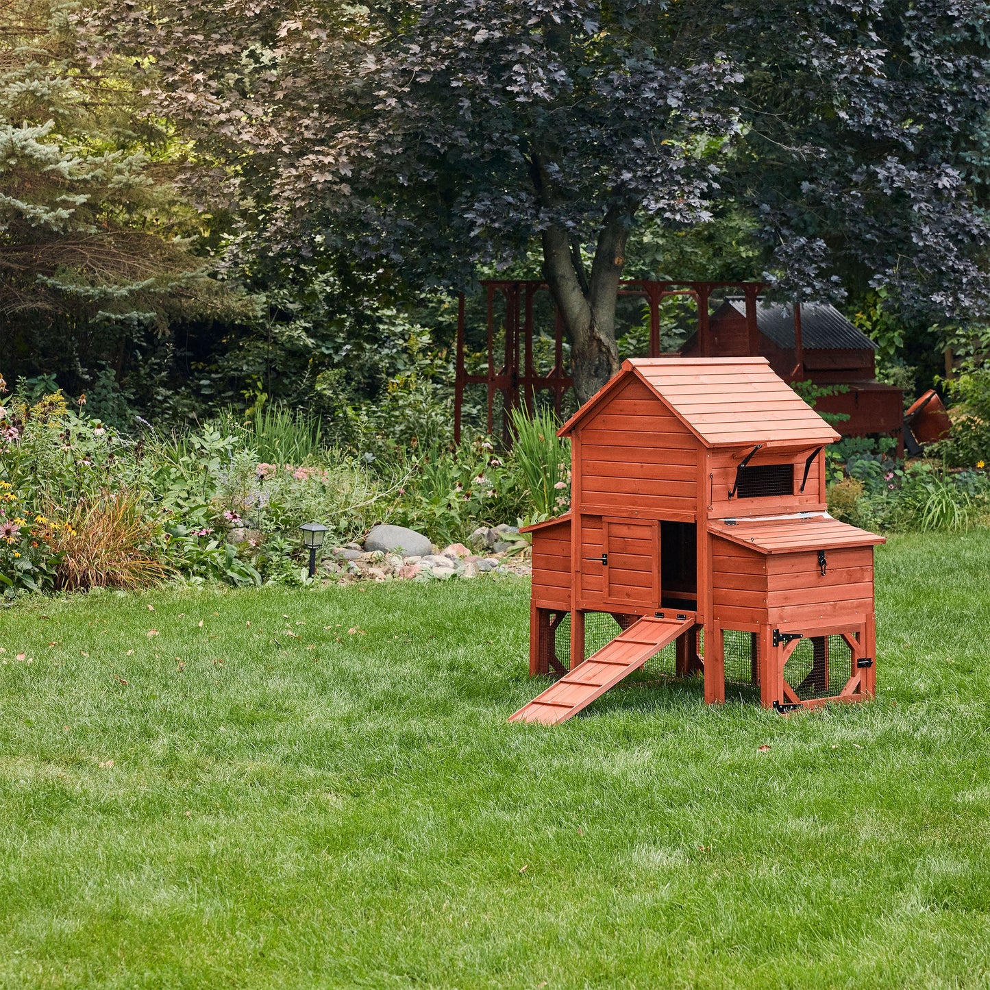 Orpington Lodge small flock chicken coop fully assembled in a lush garden setting showing warm cedar wood finish and complete enclosed run