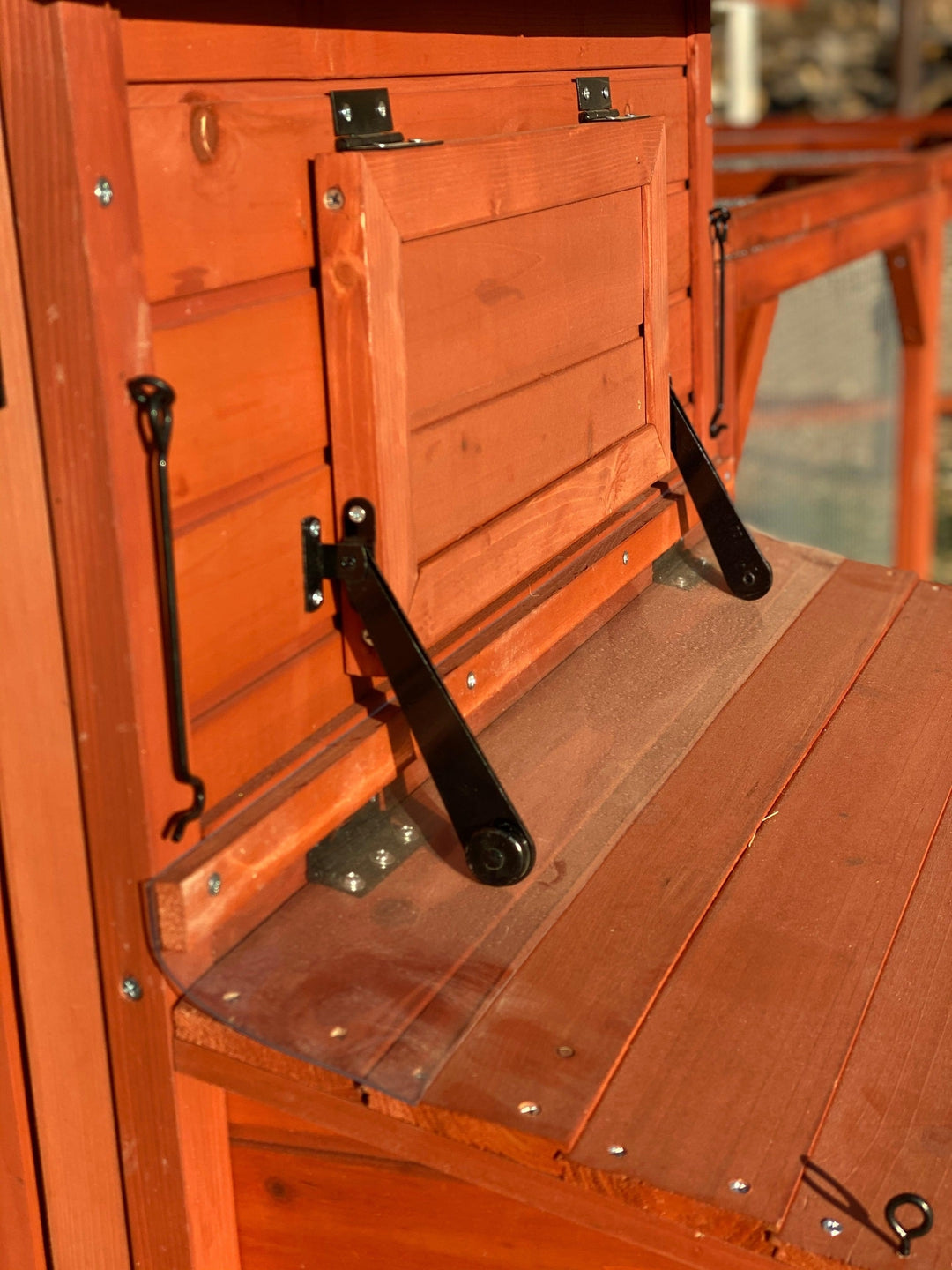 Close-up detail of Orpington Lodge chicken coop prop-open locking side vent window showing secure ventilation hardware and open position