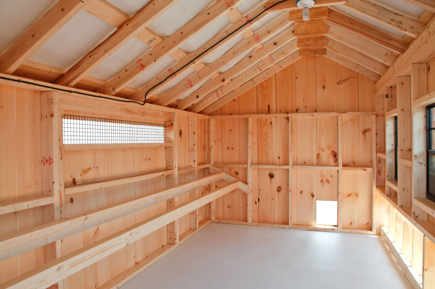 Interior of Amish-built Q712 Quaker chicken coop featuring roost bars, framed walls, and easy-clean flooring